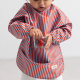 Stribet apron with long sleeves in blue and red, front pocket.