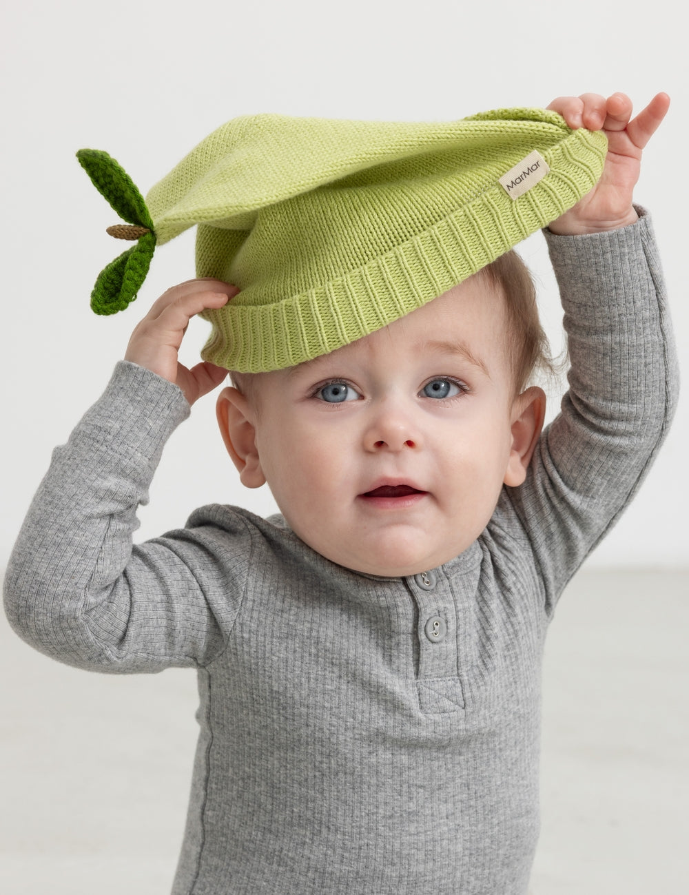 Green striped hat for baby carried by child