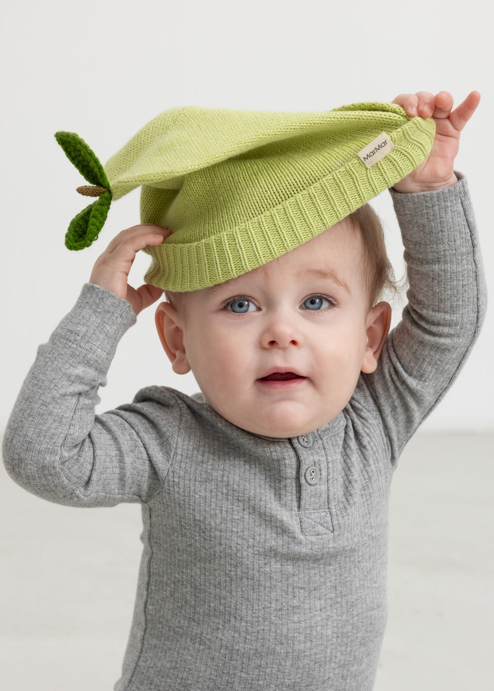 Green striped hat for baby carried by child