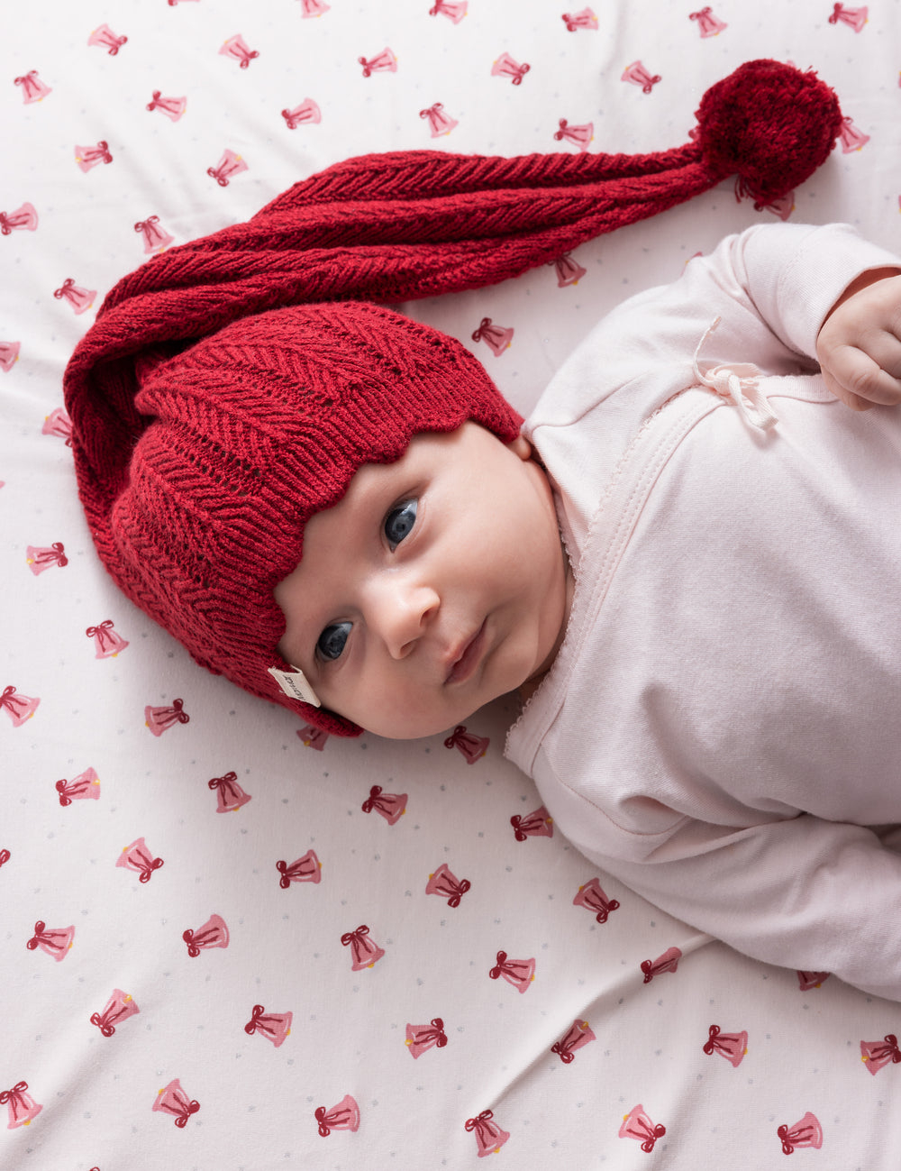 Baby wearing red knitted Santa hat with tassel and pink Christmas clothes