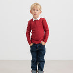 Dreng iført rød ribbluse, hvid skjorte og mørke børnejeans