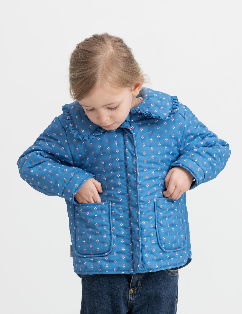 Child wearing a blue thermal jacket with floral print, collar, and pockets.