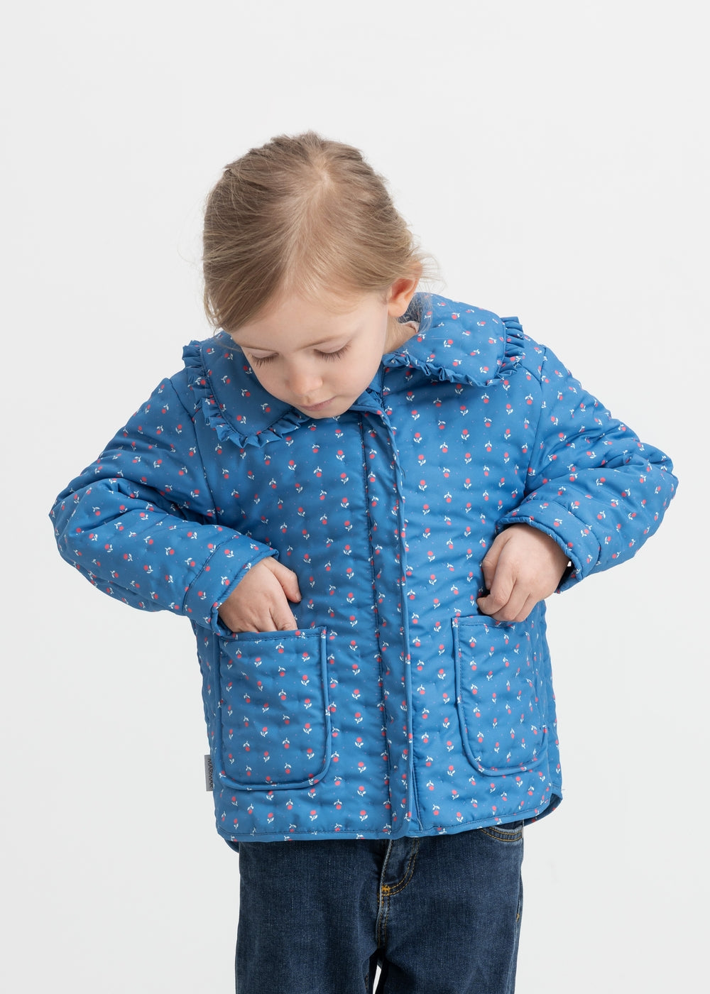 Child wearing a blue thermal jacket with floral print, collar, and pockets.