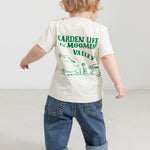 Baby wearing a white T-shirt with a green Moomin print and jeans.