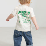 Baby wearing a white T-shirt with a green Moomin print and jeans.
