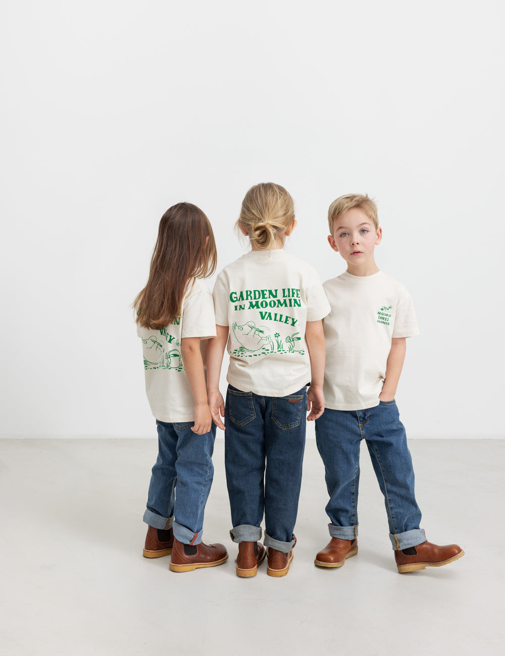 Three children wearing T-shirts with green Moomin print.