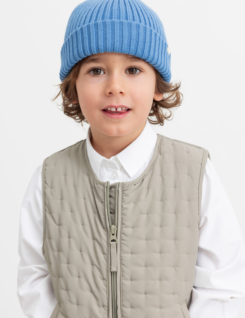 Children in the quilted vest and blue knitted hat