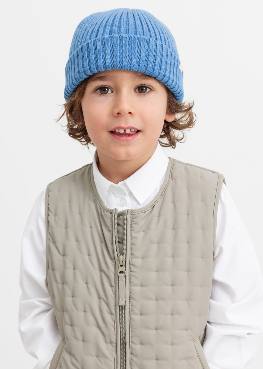 Children in the quilted vest and blue knitted hat