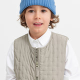 Children in the quilted vest and blue knitted hat