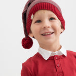 Dreng iført strikket nissehue med røde og grå striber og rød trøje til børn