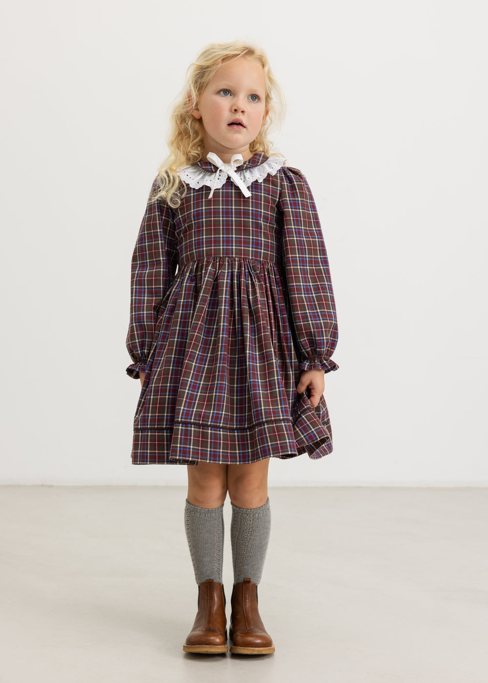 Children's dress in dark blue checkered with red check pattern, white collar and long sleeves