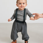 Baby iført mørkegrønne strikkede bukser med seler og grå bluse