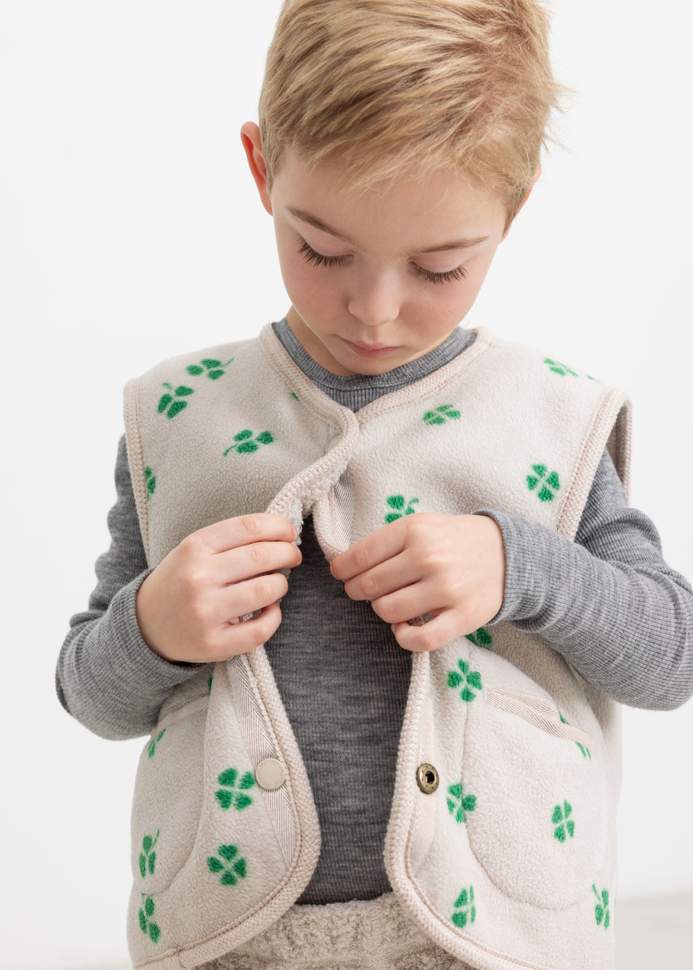 Beige vest with green clover print, closed in front