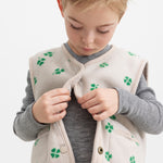 Beige vest with green clover print, closed in front