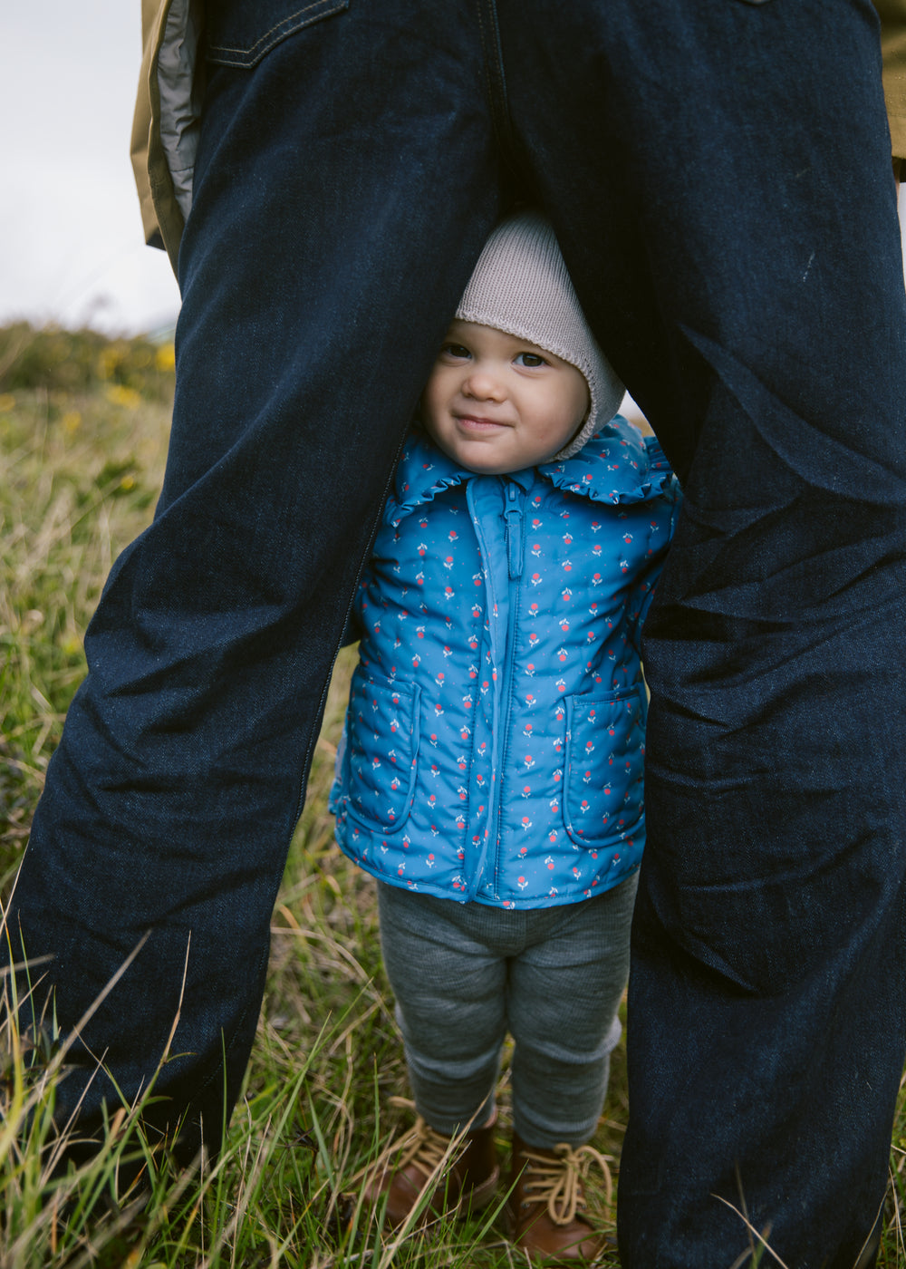 Baby wearing a blue thermal jacket with a floral print, collar, and pockets.