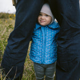 Baby wearing a blue thermal jacket with a floral print, collar, and pockets.