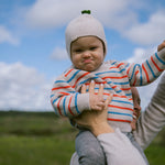 Baby is wearing a striped sweater and hat outdoors.