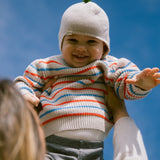 Baby wearing a knitted hat and a striped shirt.
