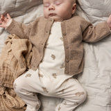 Baby onesie in white with beige teddy bear print, visible with long legs.