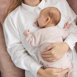Pink knitted baby shoes with laces for baby feet.