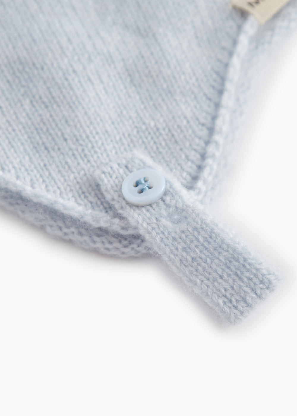 Light blue baby hat in knit with a round button on the strap.