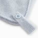 Light blue baby hat in knit with a round button on the strap.