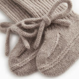 Knitted baby socks in gray-beige mélange with a tied bow at the toe.