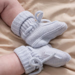 Light blue knitted baby shoes on a model with tied laces.