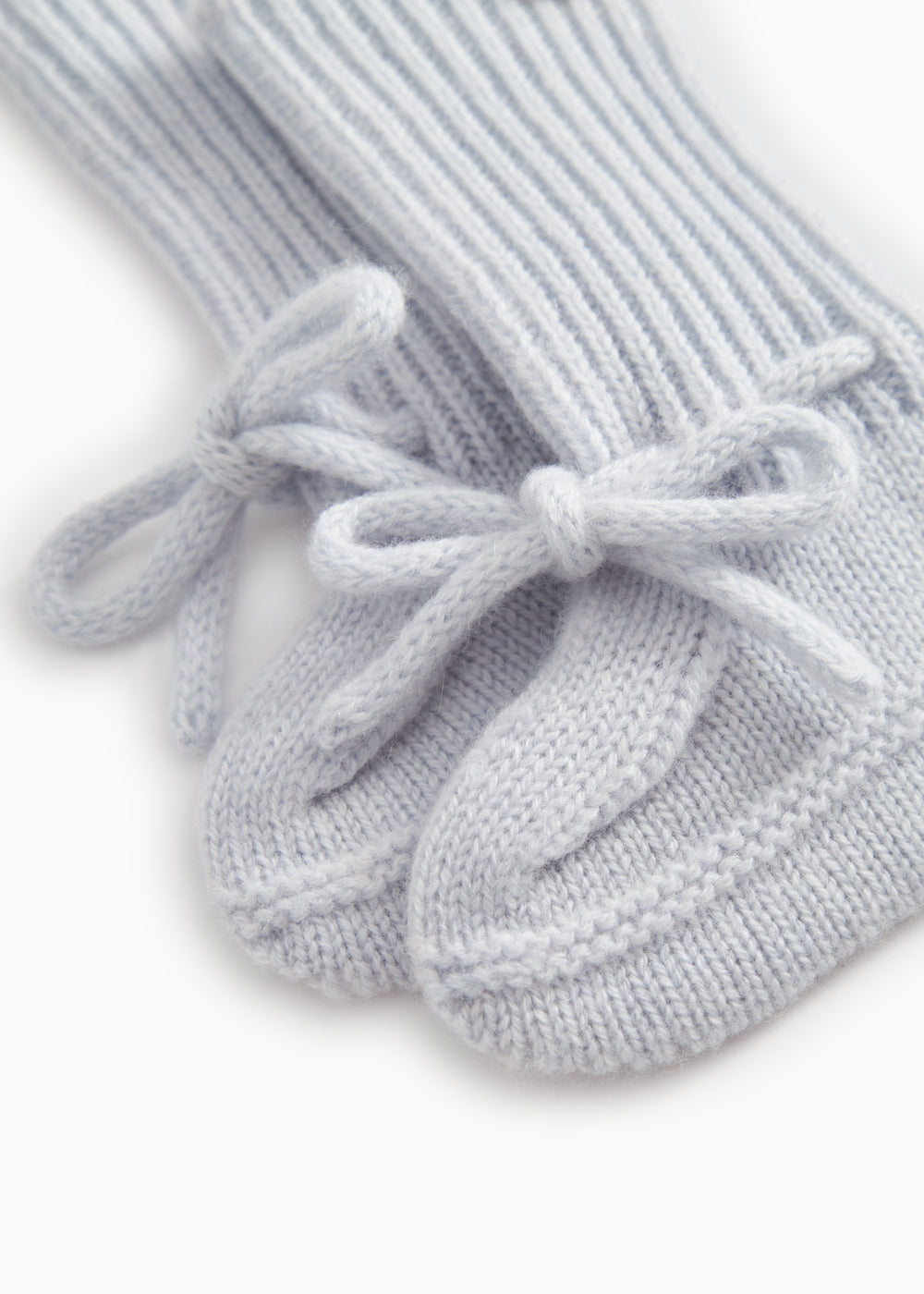 Details of light blue knitted baby shoe with tied laces.