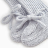 Details of light blue knitted baby shoe with tied laces.