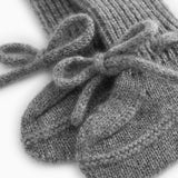 Close-up of a gray knitted baby bootie with a ruffle detail over the ribbed edge.