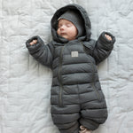 Baby ligger på tæppe iført mørkegrå dundragt