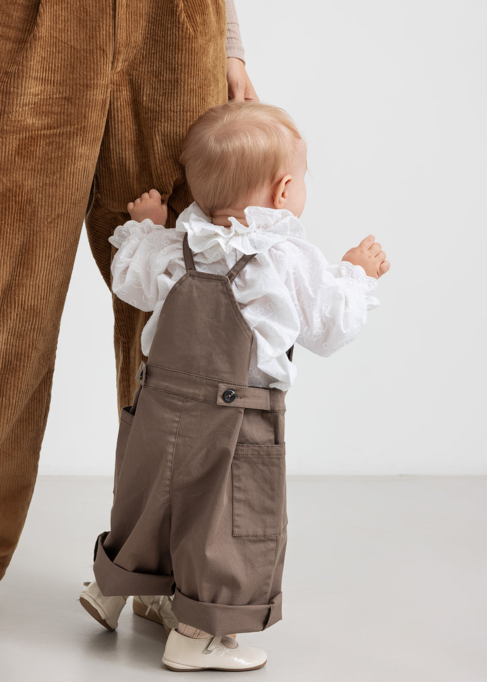 barn iført brune selebukser og hvid bluse