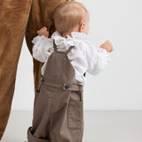 barn iført brune selebukser og hvid bluse