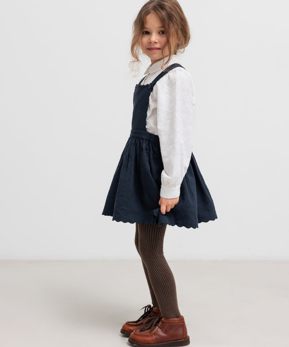 Børn iført hvid bluse og mørk nederdel