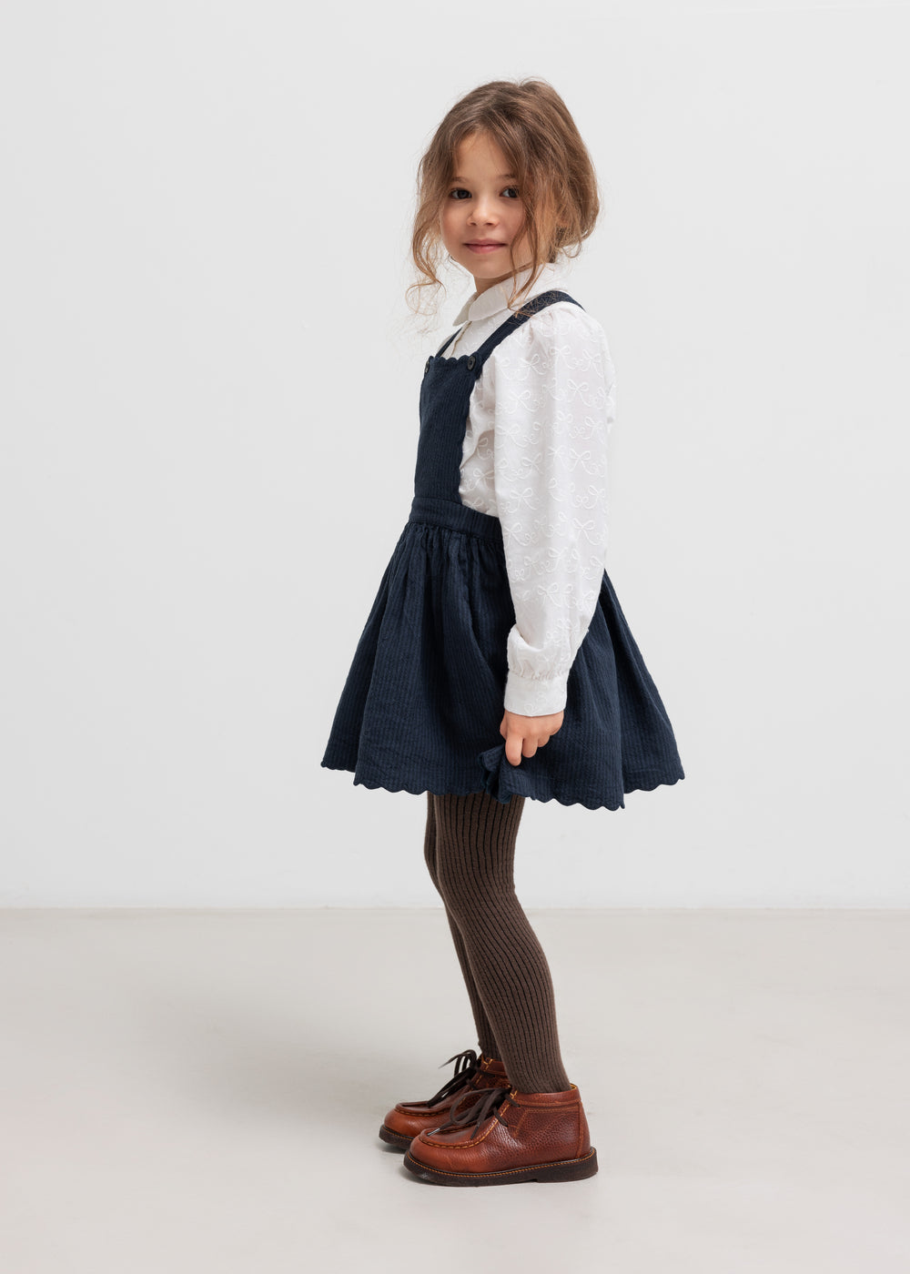 Børn iført hvid bluse og mørk nederdel