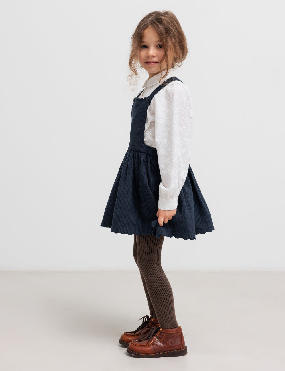 Pige iført mørkeblå sko og hvid bluse