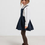 Pige iført mørkeblå selekjole og hvid bluse