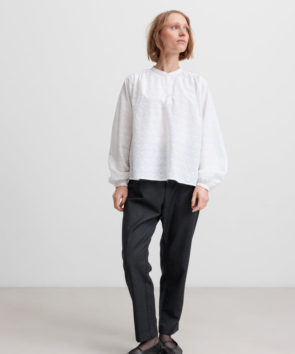 Kvinde iført hvid skjortebluse og sorte bukser