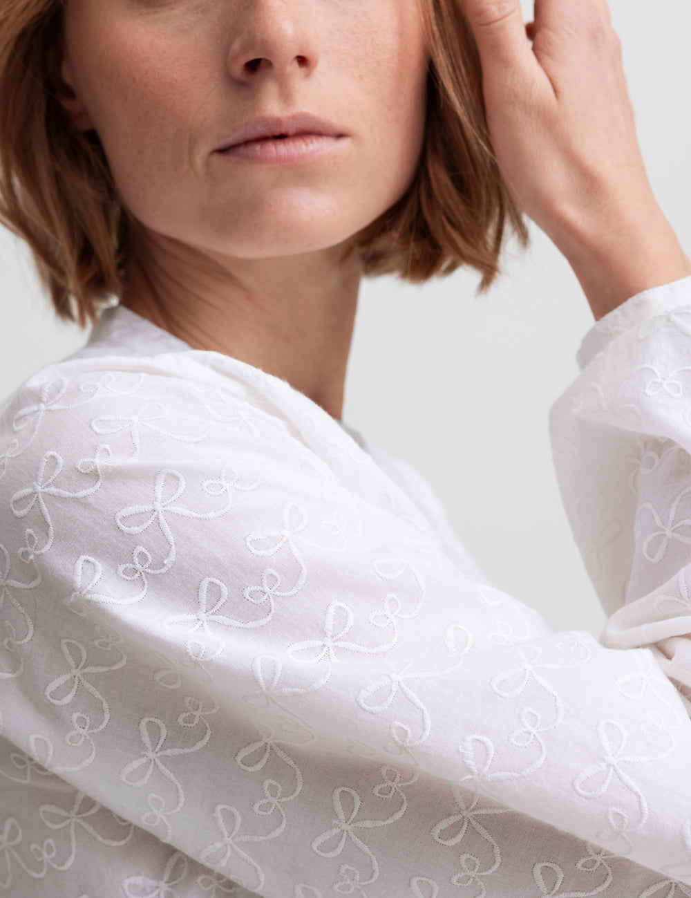 Kvinde iført hvid skjortebluse med broderet mønster