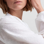 Kvinde iført hvid skjortebluse med broderet mønster