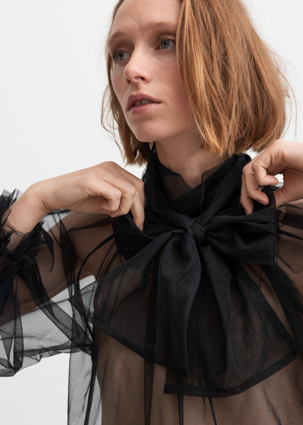 Kvinde iført sort gennemsigtig tylbluse med stor sløjfe