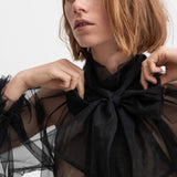 Kvinde iført sort gennemsigtig tylbluse med stor sløjfe