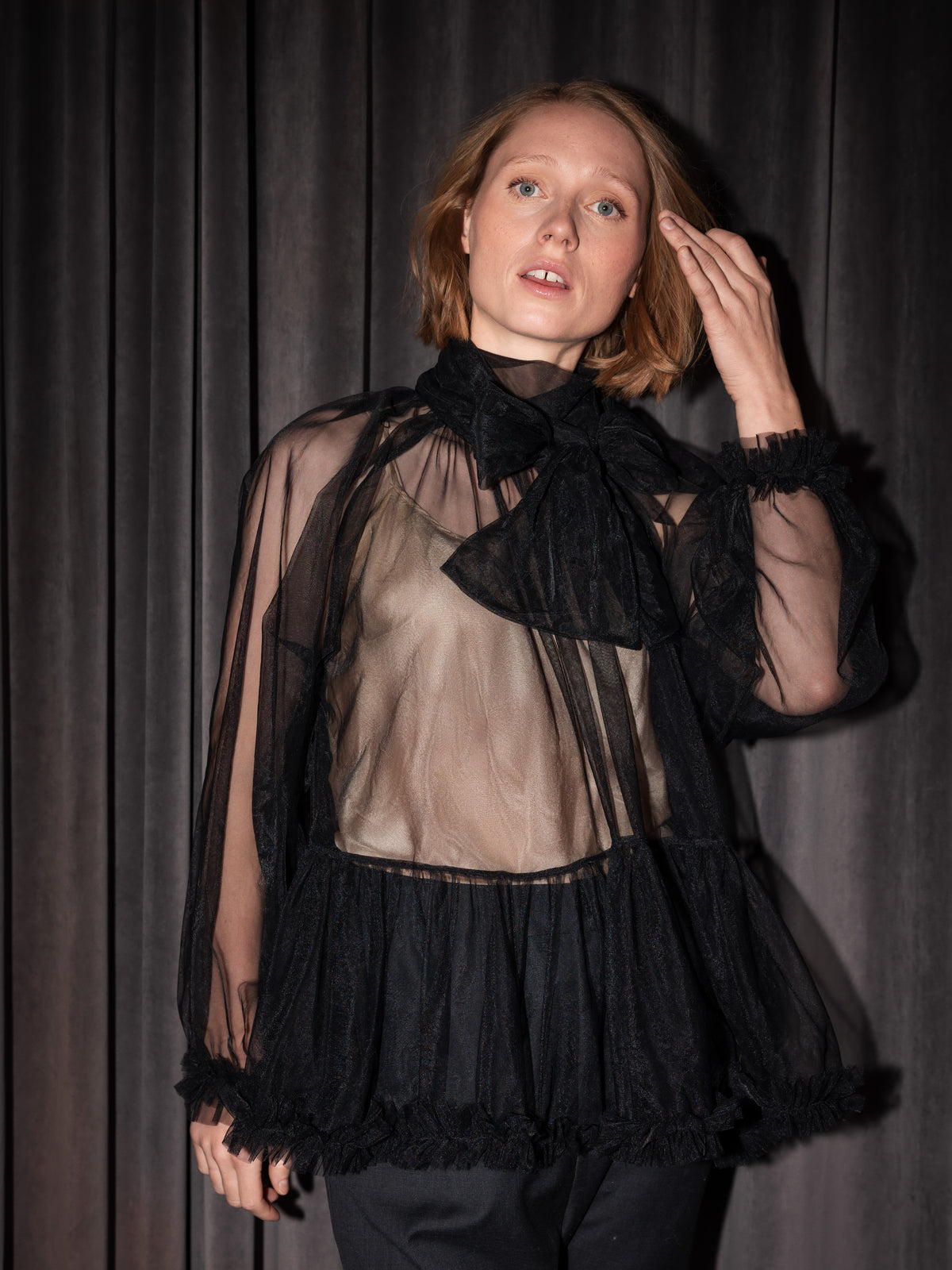 Kvinde i sort gennemsigtig festbluse med stor sløjfe ved halsen