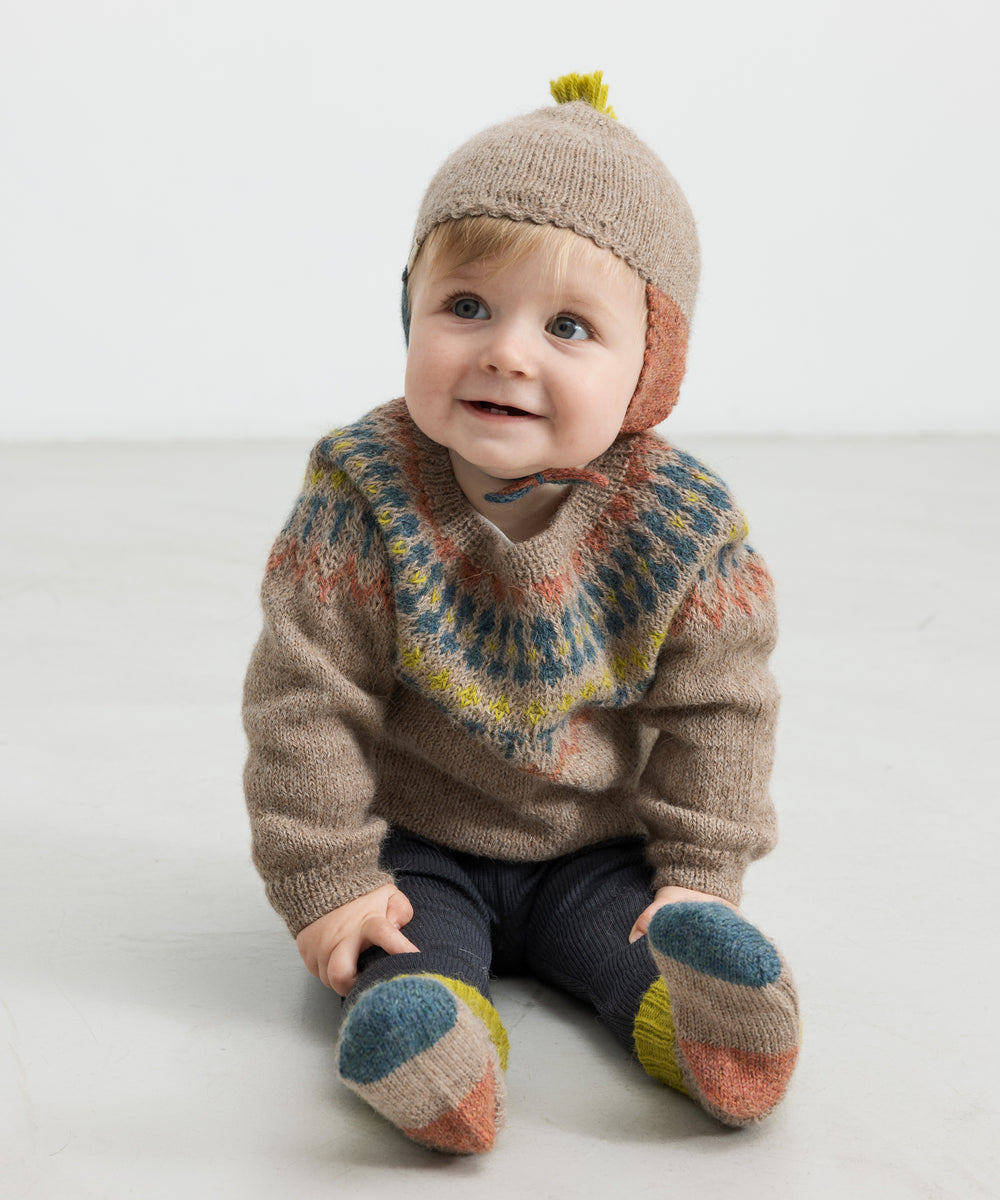 Barn med uldstriksokker, beige hue og mønsterstrik