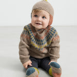 Baby iført beige uldhue med kvast og strikket trøje