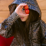 Barn iført leopardmønstret regnjakke me hætte, kigger gennem et tomatstykke