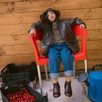 Barn sidder på en rød stol iført leopardmønstret regnjakke og jeans