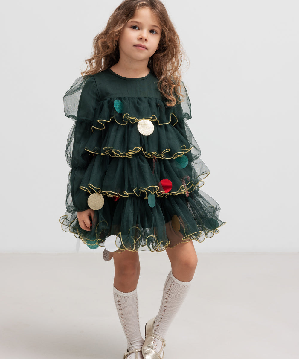 Pige iført mørkegrøn julekjole i tyl med guldkanter og juledetaljer til børn