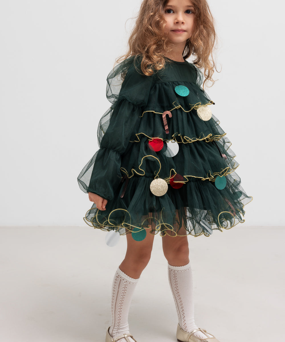 Pige iført mørkegrøn julekjole i tyl med guldkanter og juledetaljer til børn